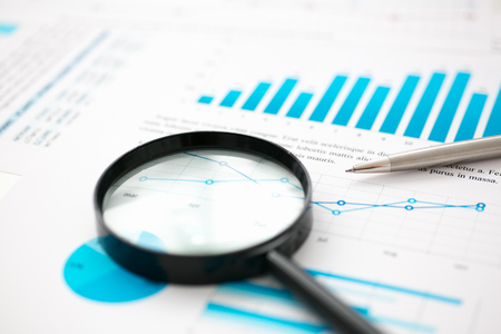 Financial statistics documents on lens and pen office table closeup. Internal Revenue Service inspector sum check, irs investigation, exchange market, earnings, savings, loan and credit conceptの写真素材