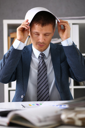 A man experiences stress and a headache in the workplace experiences negative emotions from paper red tape trouble personality disorder and career growth lack of knowledgeの写真素材