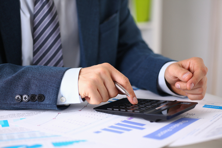 Black calculator and financial statistics on infographics at office table closeup. Internal Revenue Service inspector sum check, irs investigation, earnings, savings, loan and credit conceptの写真素材