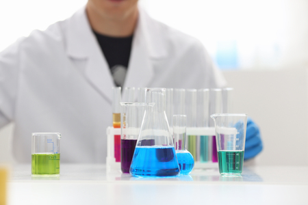 A male chemist holds test tube of glass in his hand overflows a liquid solution of potassium permanganate conducts an analysis reaction takes various versions of reagents using chemical manufacturingの写真素材