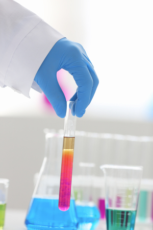 A male chemist holds test tube of glass in his hand overflows a liquid solution of potassium permanganate conducts an analysis reaction takes various versions of reagents using chemical manufacturingの写真素材