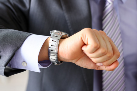 Man in suit and tie check out time at silver wristwatch closeup. Waste minute, modern punctual life style, start hurry, job idea, last second, clockwork precision conceptの写真素材