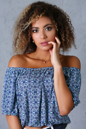Beautiful black woman portrait. It's a gray background and does not smile beauty fashion style mulatto curly hair with white strands look the eye into the cameraの写真素材