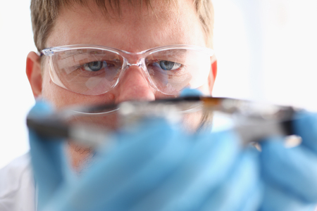 A male repairman wearing blue gloves is holding a hard drive from computer or laptop in hands. Performs fault diagnostics and performs urgent repairs recovery of lost data during deletion HDD closeupの写真素材