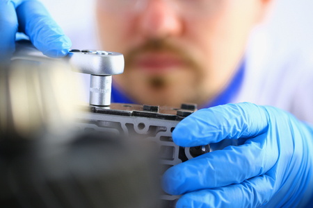 Repairman car-care center on repair of automatic transmissions holds in hand horn key carries out disassembling assemblage hydroblock detail carries diagnostics makes an estimation of working capacityの写真素材