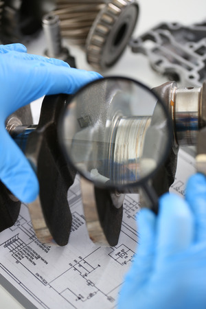 The mechanic of the service center for engine repair considers problem crankshaft on which as a result of bad lubrication of oil starvation there was a breakdown and the appearance of scuffing linersの写真素材