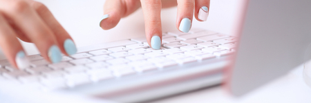 Female hands typing on silver keyboard using computer pc