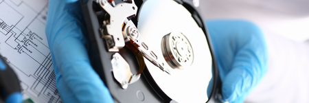 male repairman wearing blue gloves is holding a hard drive