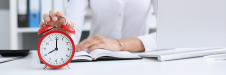 Smiling business woman holding in hand clockの写真素材