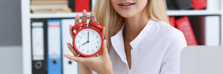 Smiling business woman holding in hand clockの写真素材