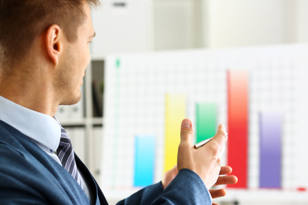 Man in suit point with arm in stats graphの写真素材