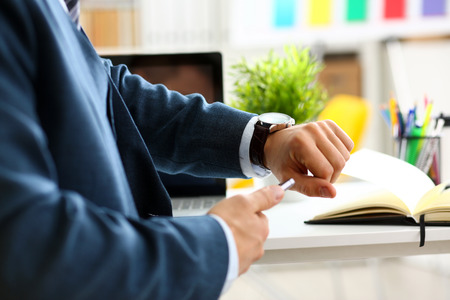 Man in suit and tie check out time at silver wristwatchの写真素材