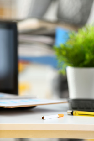 Cigarette and lighter lying at worktableの写真素材