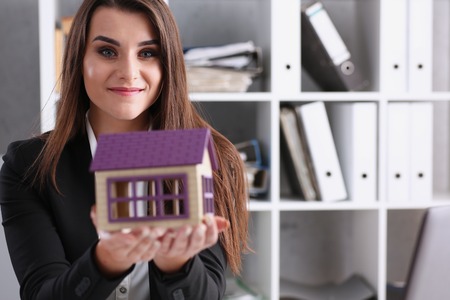 Businesswoman in the office holds a miniatureの写真素材