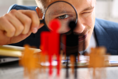Man in suit look thru loupe on statuettes closeupの写真素材