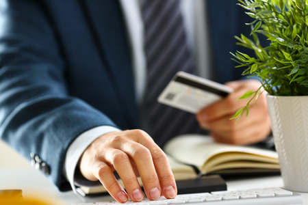 Male arms hold credit card press buttons making transferの写真素材