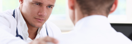 Friendly male doctor hold patient shoulderの写真素材