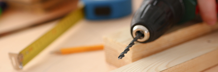 Arms of worker using electric drill