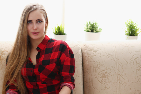 young blond woman sit on sofa in roomの写真素材