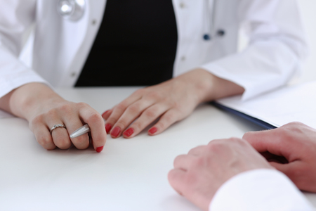 Female doctor hand hold silver pen filling patientの写真素材
