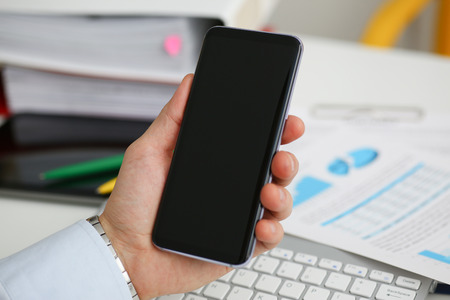 A businessman holds a new smartphone in