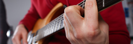 Male arms playing classic shape electric guitar