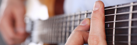 Male arms playing classic shape electric guitar