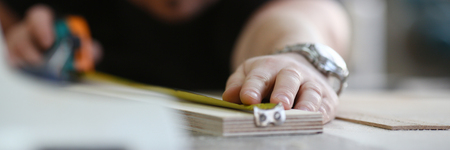 Arms of worker measuring wooden bar closeupの写真素材