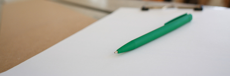 Drafting green pen lying on desk on clipboard