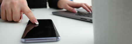 Female arm hold phone and silver pen at workplace closeupの写真素材