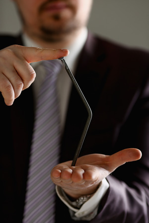 Man in suit and tie bend nail with arms closeupの写真素材