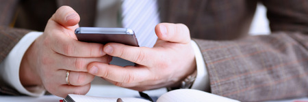Male arm in suit hold phone and silver penの写真素材