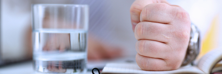 Male clenched fist in suit at officeの写真素材