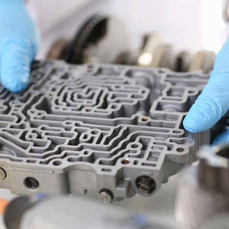 The auto repair service repairman automatic gearboxes holds in his hand in blue protective gloves...