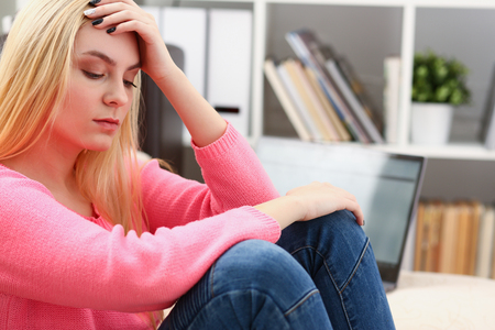 Unhappy lonely depressed woman sitting on the couchの写真素材