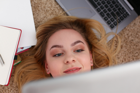 young beautiful woman lie on floor have a lot of work hold tablet in armsの写真素材