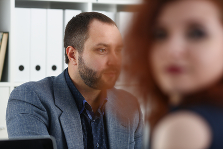 young beautiful red haired woman sit at table in office in cabinet of her bossの写真素材