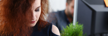 young beautiful red haired woman sit at table in office in cabinet of her bossの写真素材