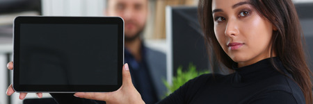 young pretty brunette woman in office hold tablet in handsの写真素材