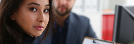 young beautiful woman sit on chair at table in office in cabinet of her boss hold binder in armsの写真素材