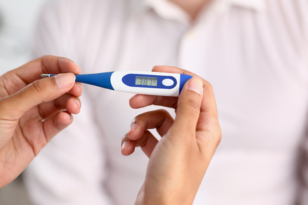 hands of a female doctor holding a thermometer