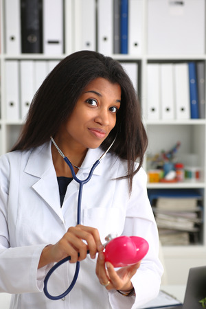 A beautiful black smiling female doctor holding a red heartの写真素材