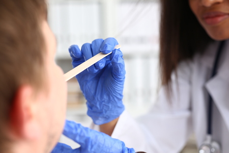 A beautiful black smiling female doctor examining a patientの写真素材