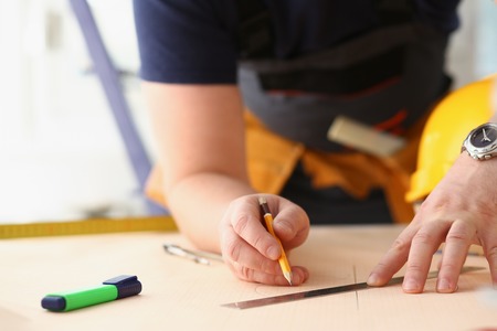 Arms of worker making structure plan on scaled paper closeup