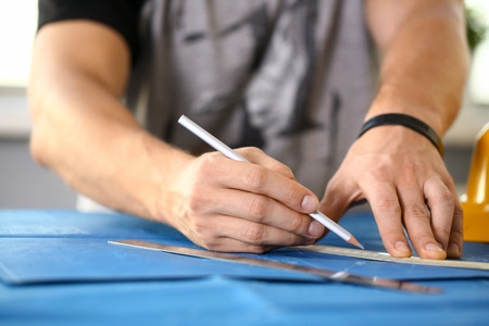 Male hand holding pencil in hand. Engineering blueprint design for buildings of blue architecture...
