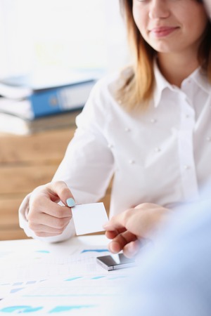Female hand in suit give blank business card to her friendの写真素材