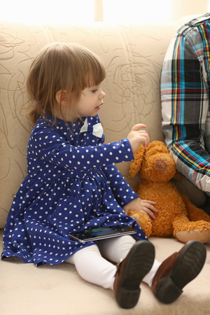 Cute little girl on couch use cellphoneの写真素材