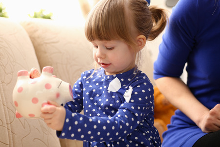 Child little girl arm putting coins into piggybankの写真素材