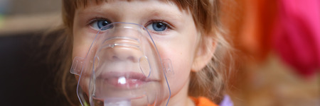 Happy child makes inhalation at home for