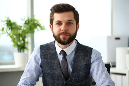Handsome smiling bearded clerk man at workplace look in camera